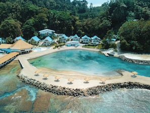 A resort with a large pool, beach area, and multiple buildings with blue roofs. - Ordovician Beach Resort (Isla Grande)