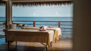 A spa area with two massage tables, a wooden deck, and a view of the ocean.