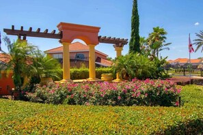 Stroll through the serene garden, surrounded by lush greenery and vibrant flowers beneath a shaded pergola.
