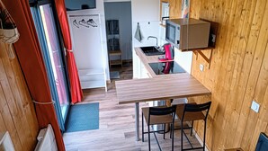 A compact kitchen with a microwave, kettle, and a small table with chairs.