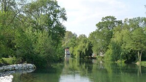 A serene riverside scene with a stone wall and lush greenery.