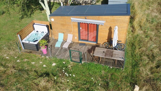 A wooden cabin with a hot tub, a covered deck, and a bicycle.