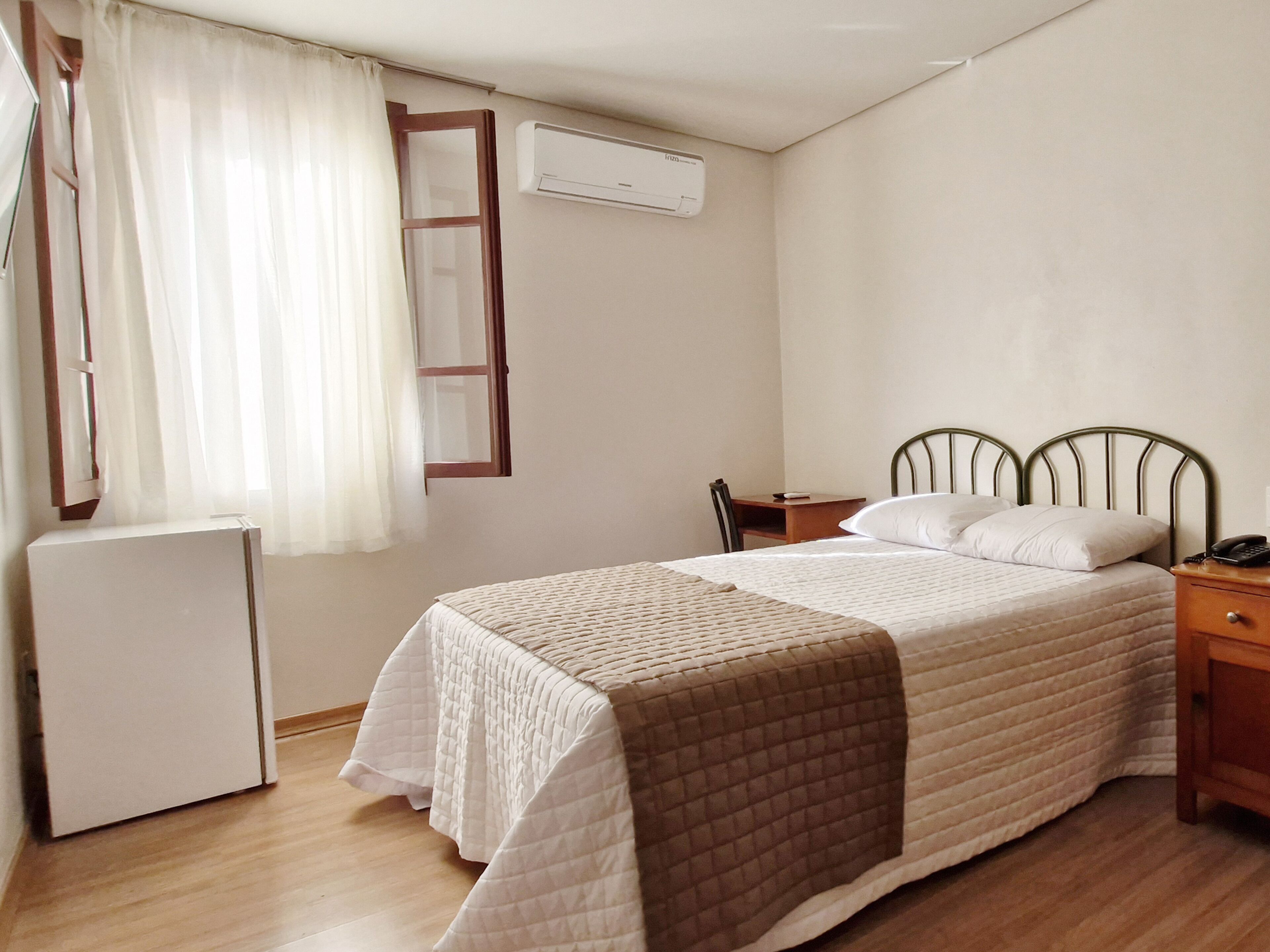 Un dormitorio con cama, mesita de noche, silla y un pequeño escritorio.