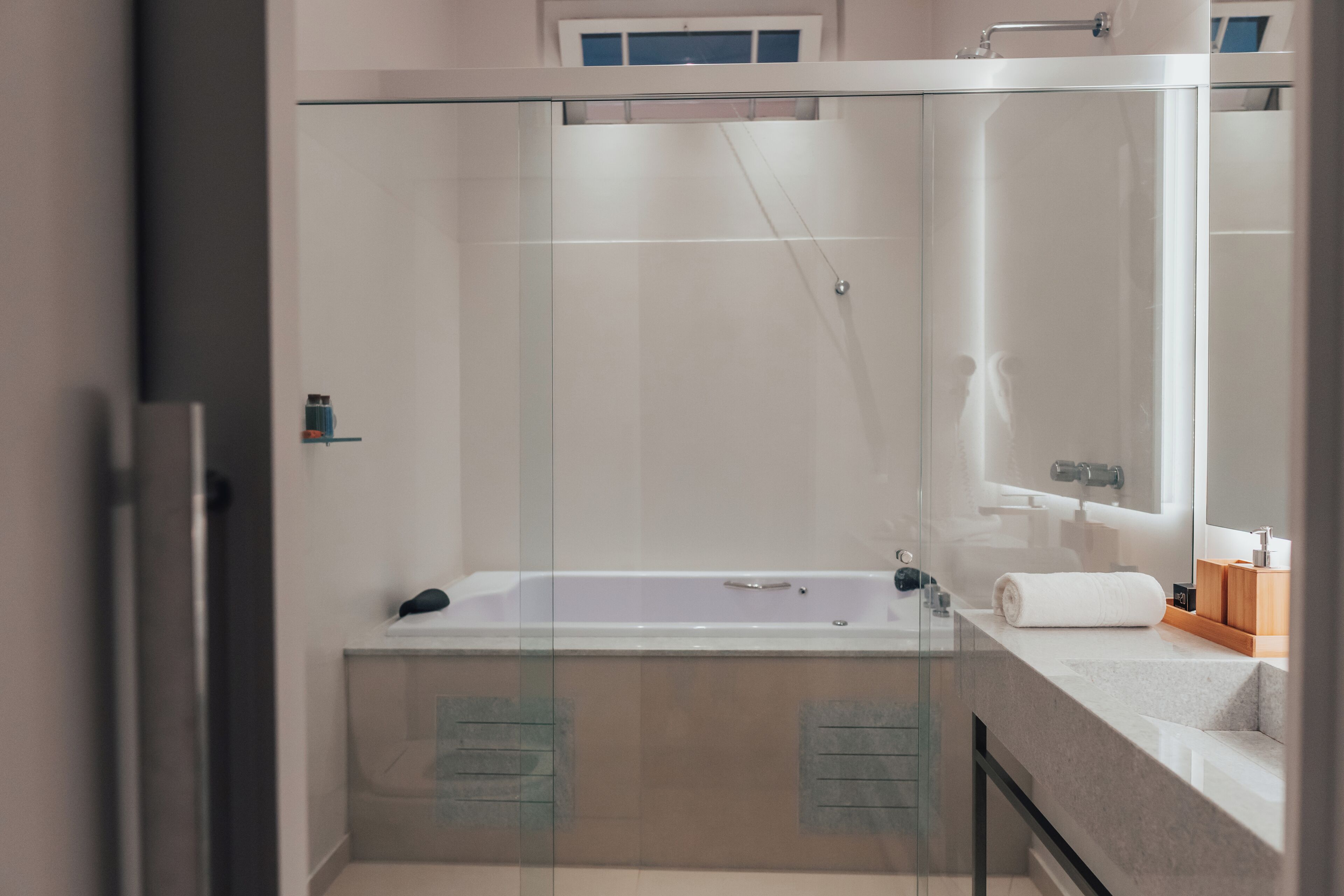 Un baño moderno con ducha envuelta en vidrio, una bañera blanca y un tocador con espejo.