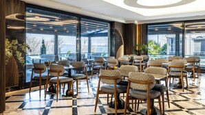 A modern restaurant with a checkered floor, patterned chairs, and large windows offering a city view. - Ezkar Bathonea Art İstanbul Hotel (Istanbul)