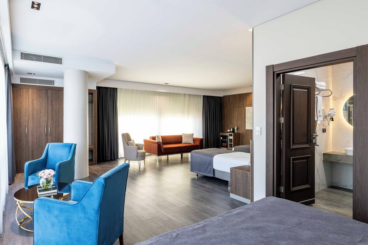 A modern hotel room with a bed, a sofa, a coffee table, and a desk.