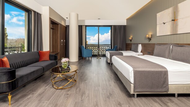 A modern hotel room with a large bed, a sofa, a coffee table, and a balcony with a view. - Ezkar Bathonea Art İstanbul Hotel (Istanbul)