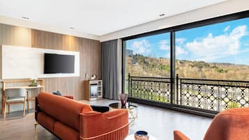 Un salon moderne comprenant un canapé, un téléviseur, un coin repas et un balcon avec vue.
