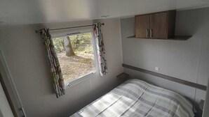 Un dormitorio pequeño con cama, una ventana con cortinas y un armario.