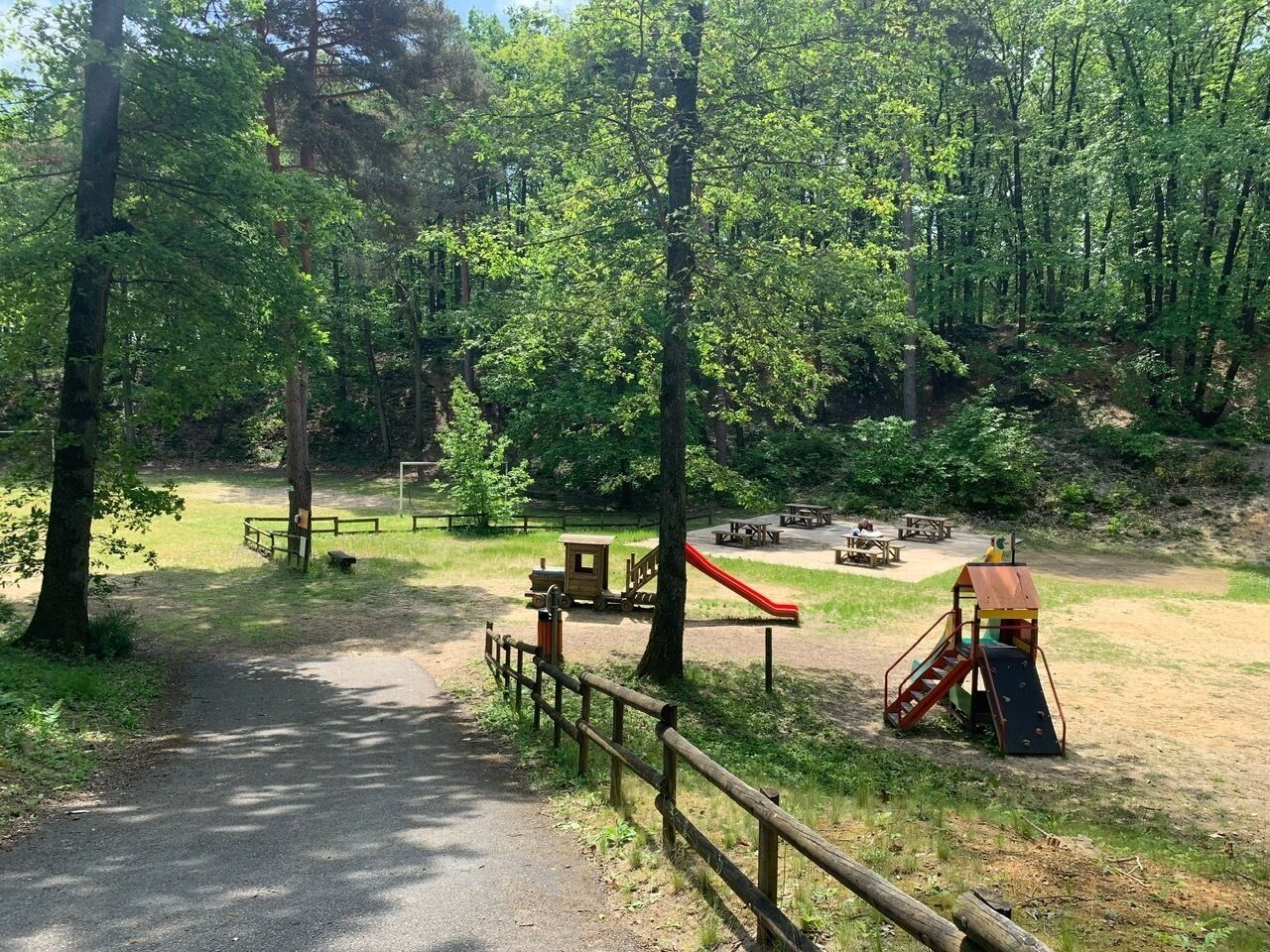 A park with a playground, picnic tables, and a dirt path.