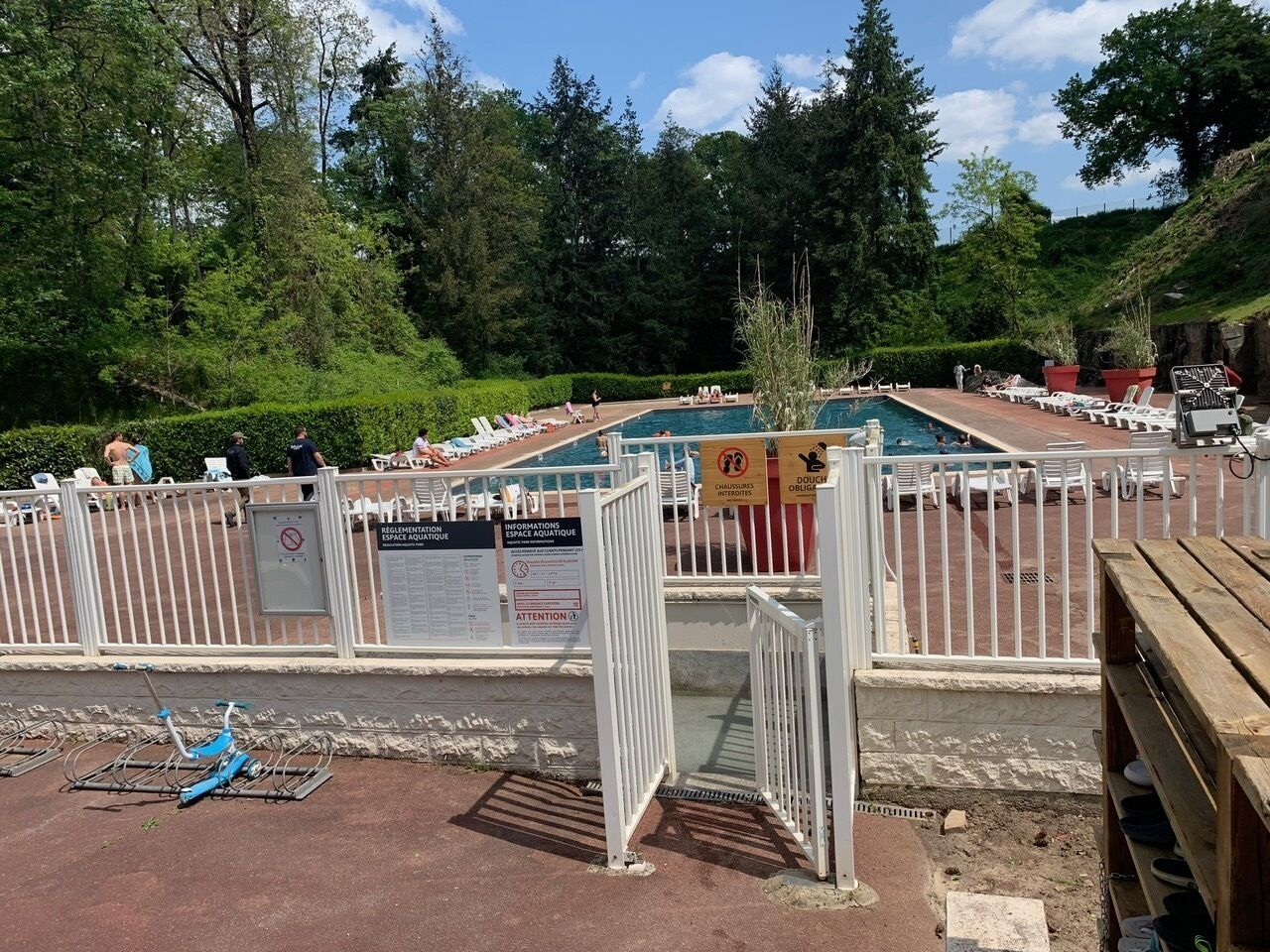 Uma área de piscina com cerca branca, placas e espreguiçadeiras.