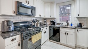 A modern kitchen with white cabinets, a stainless steel stove, a microwave, and a dishwasher. - Updated Arlington Townhome ~ 5 Mi to National Mall (Arlington)