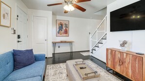 A living room with a blue sofa, a wooden cabinet, a ceiling fan, and a staircase. - Updated Arlington Townhome ~ 5 Mi to National Mall (Arlington)