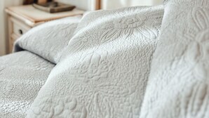 A bed with a quilted cover, a bedside table with a lamp, and a mirror. - Apartamento ThatsHome Silgar 4 (Sanxenxo)