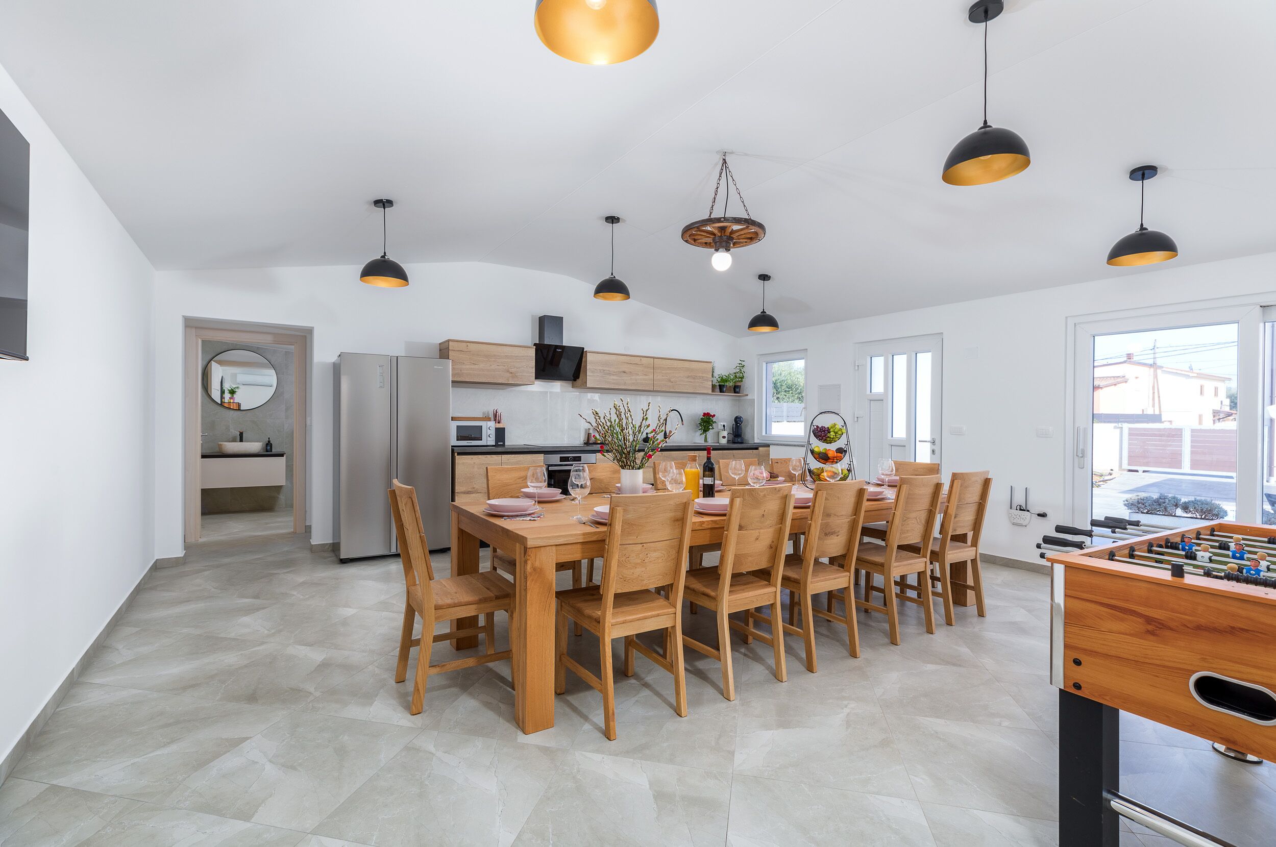 Una cocina amplia con comedor, muebles de madera e iluminación colgante.