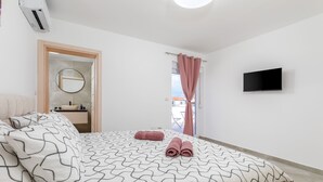 A bedroom with a bed, a TV, a bathroom, and a view of the outside. - Brand new 6 bedroom villa, only 1500m from the beach, village Valbandon (Valbandon)