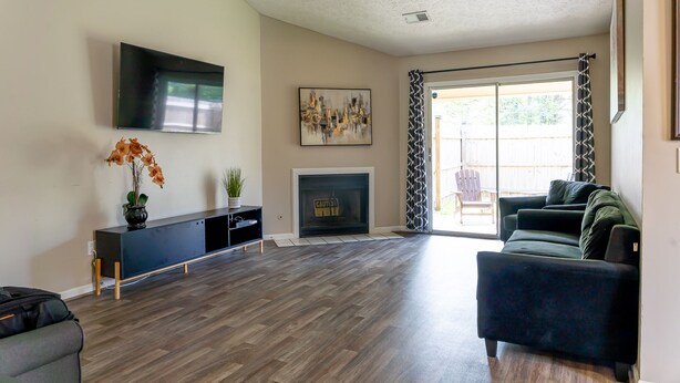 A living room with a flat-screen TV, a fireplace, a sofa, and a sliding glass door leading to a patio. - Welcome!  The Darby House is named for Colonel William O Darby (Columbus)