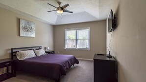 A bedroom with a bed, a ceiling fan, a window, and a TV mounted on the wall. - Welcome!  The Darby House is named for Colonel William O Darby (Columbus)