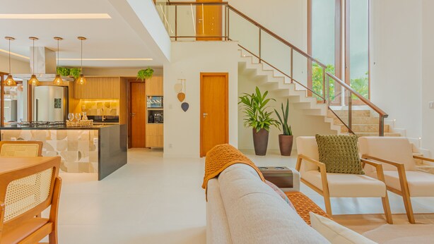 Un grand espace de vie comprenant un canapé, des fauteuils, une table à manger, une cuisine et un escalier.