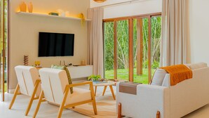 Un salon moderne comprenant un téléviseur, un canapé, des fauteuils et une table à manger.