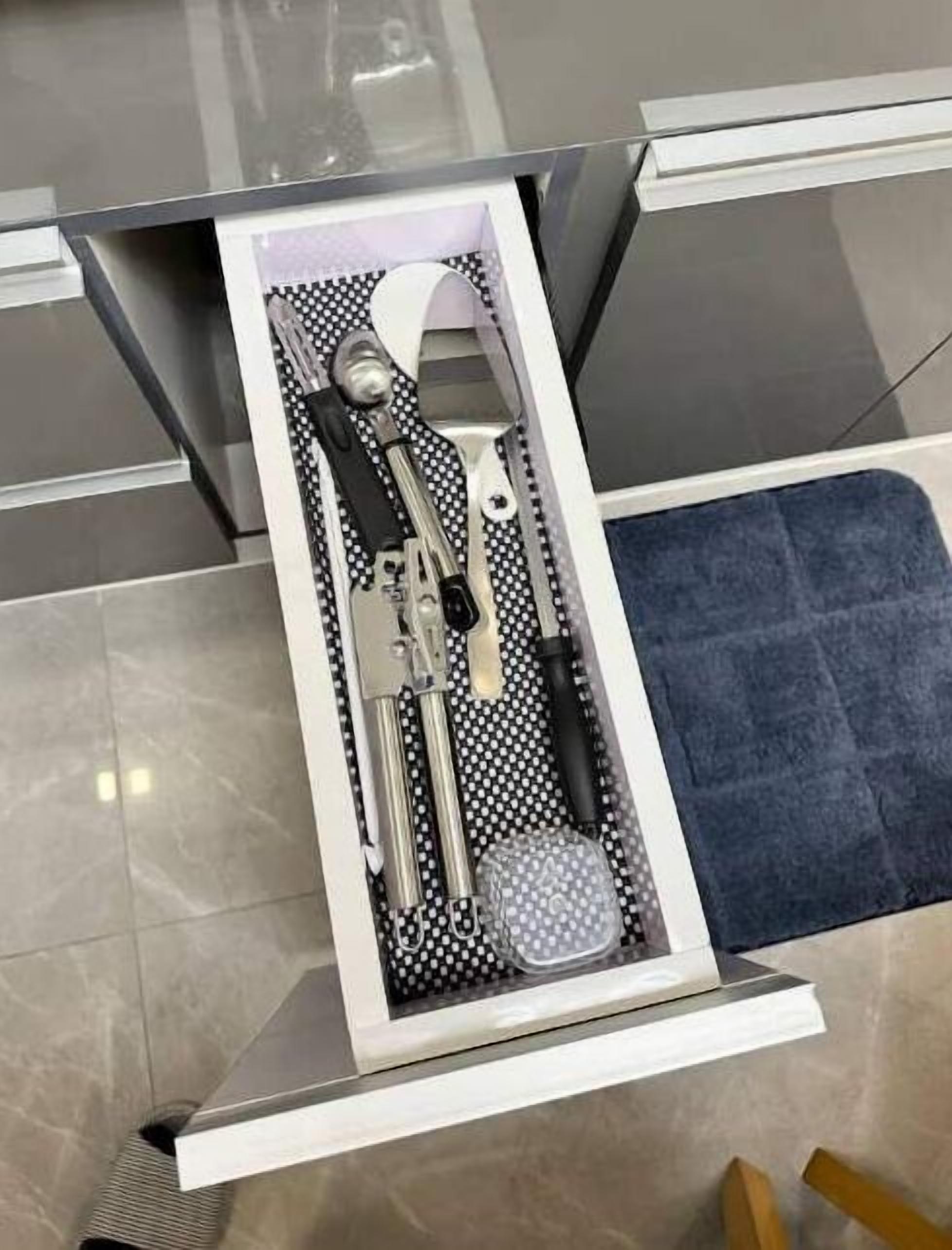 A drawer with a black and white polka dot interior, containing various kitchen utensils.