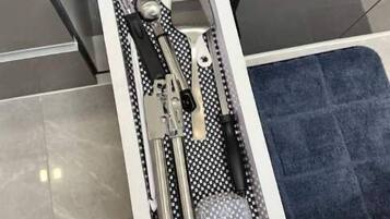 A drawer with a black and white polka dot interior, containing various kitchen utensils.