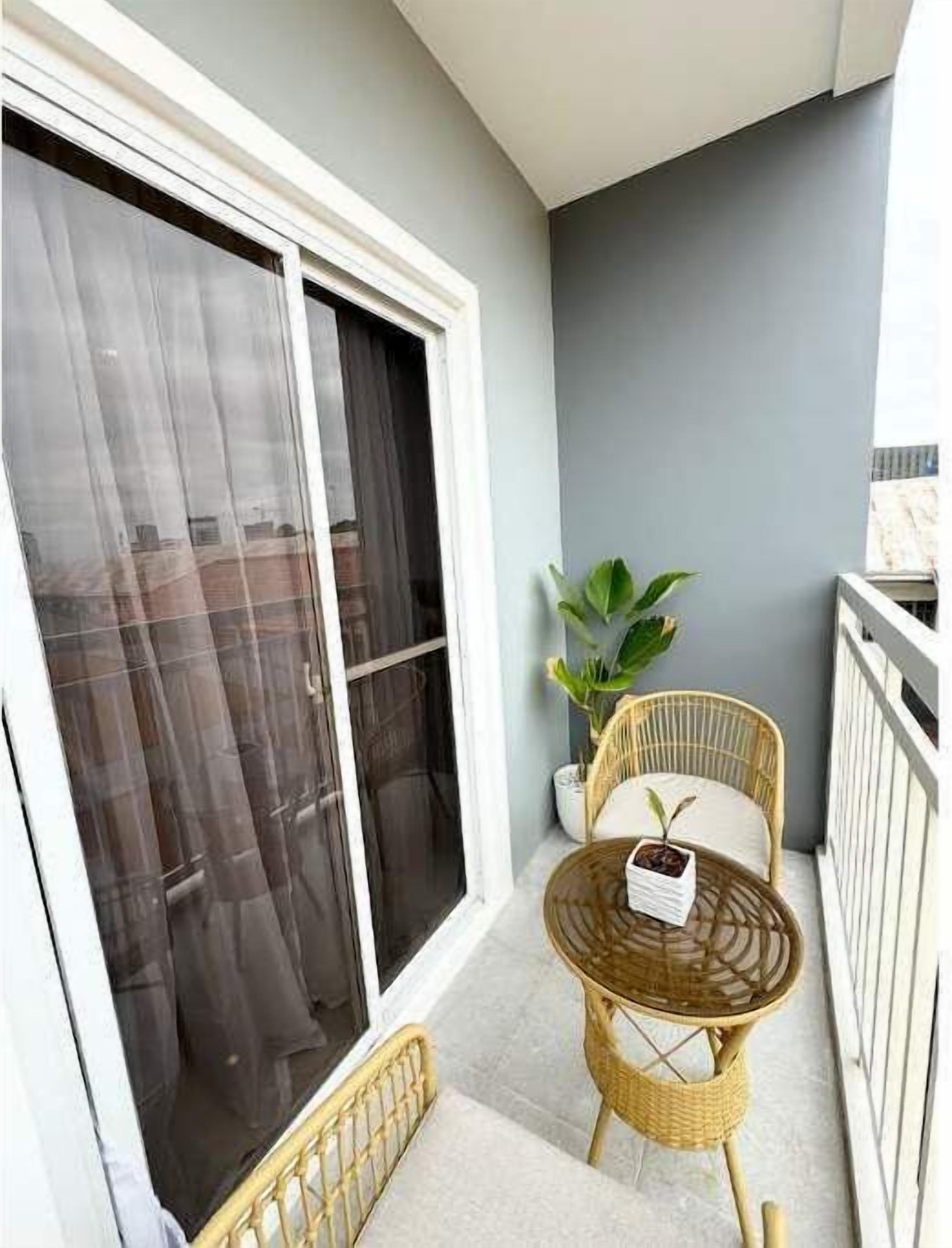 A balcony with a sliding glass door, a wicker chair, a small table, and a potted plant.