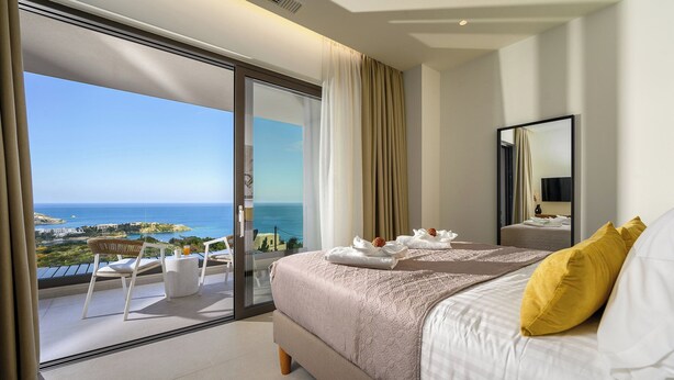 A hotel room with a bed, a balcony with a view of the sea, and a dining area with a table and chairs. - Kyma Majo Luxury Sea View Villa 6-Bedroom with Gym,Sauna,Heated Private Pool (Malevizi)