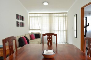 Enjoy meals in this stylish dining area with a wooden table, comfortable sofa, and unique chair.