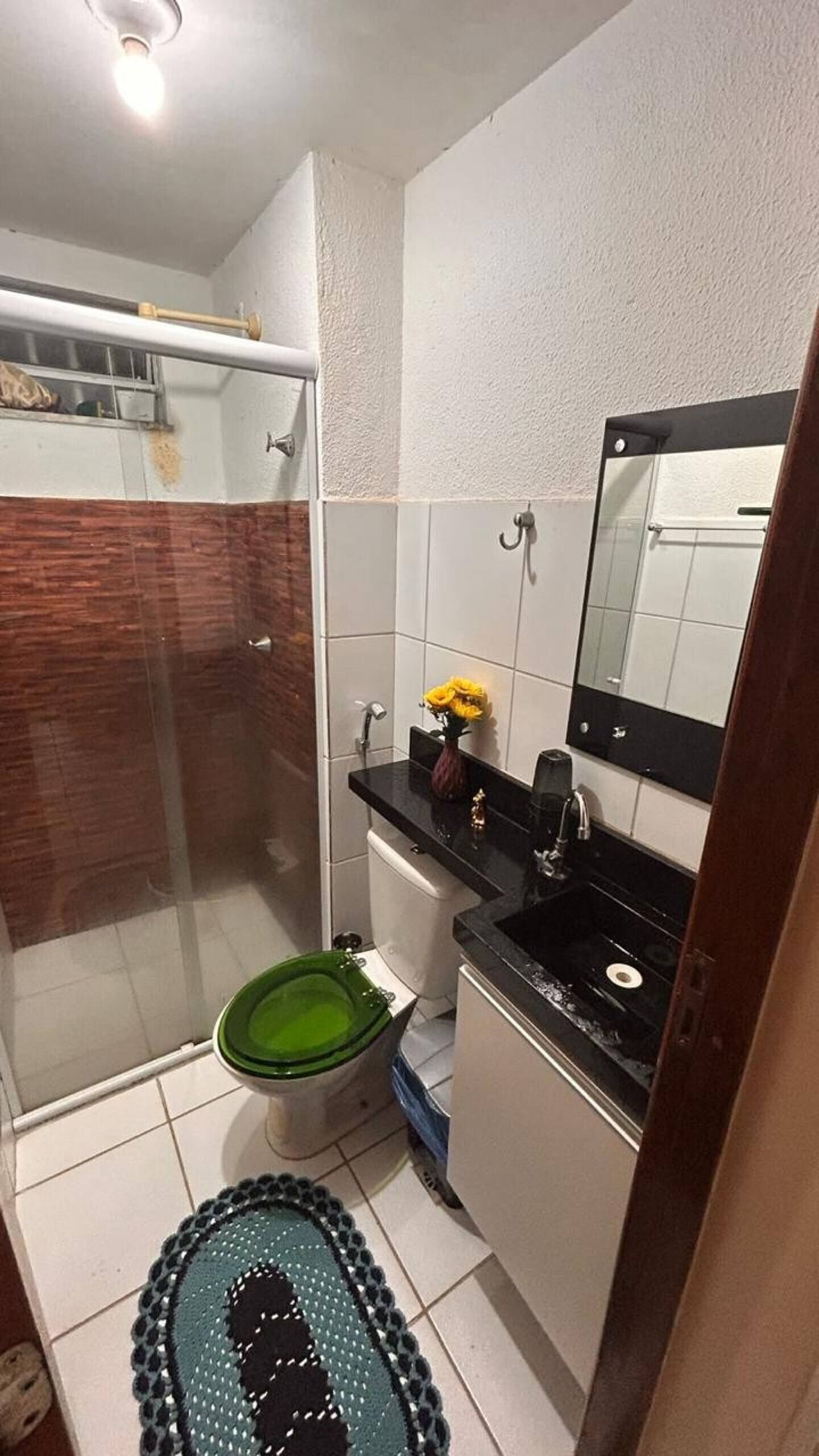 A bathroom with a shower, toilet, sink, and a mirror.
