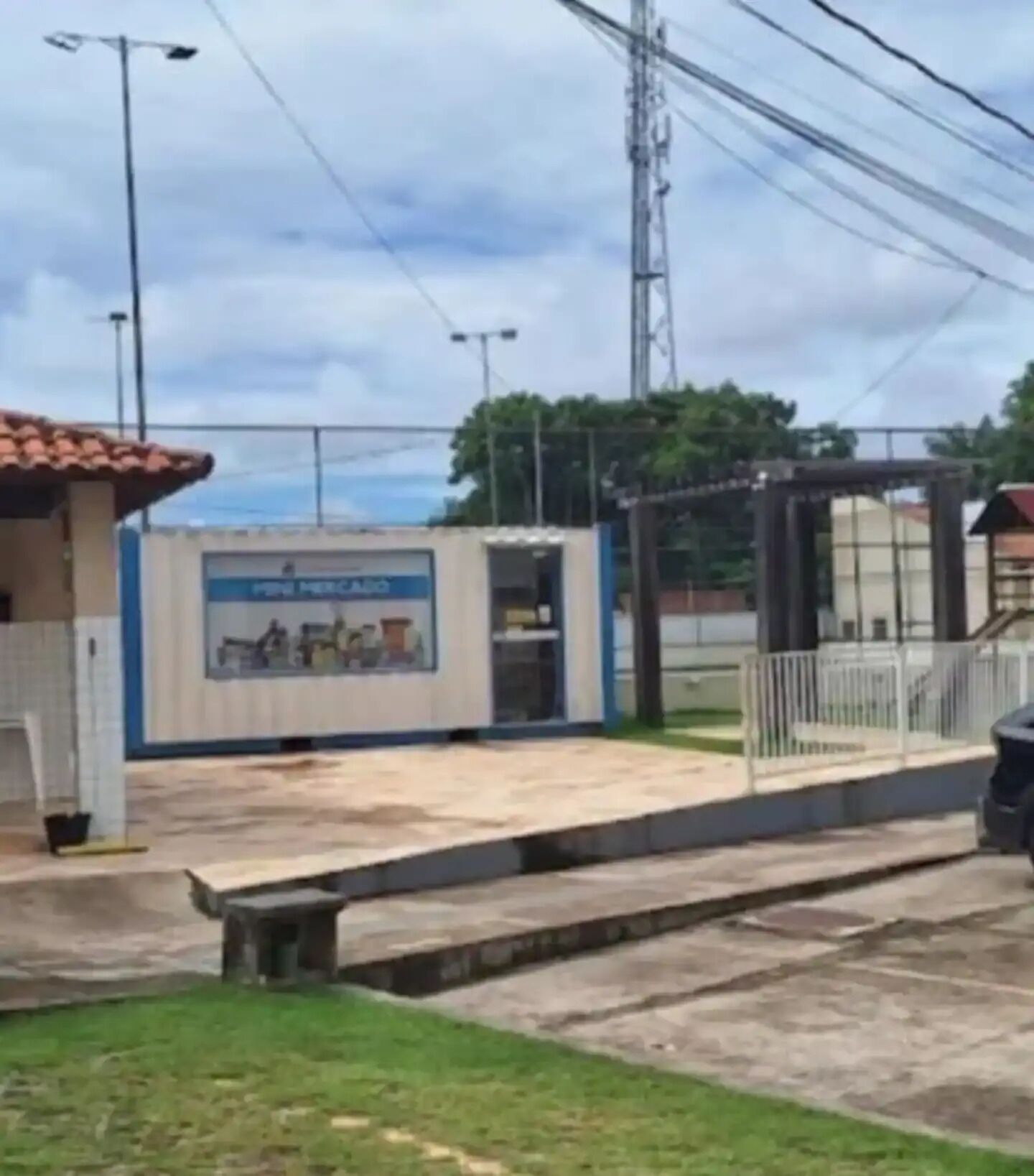 Un petit bâtiment avec un toit en tuiles, une enseigne et une zone délimitée par une clôture.