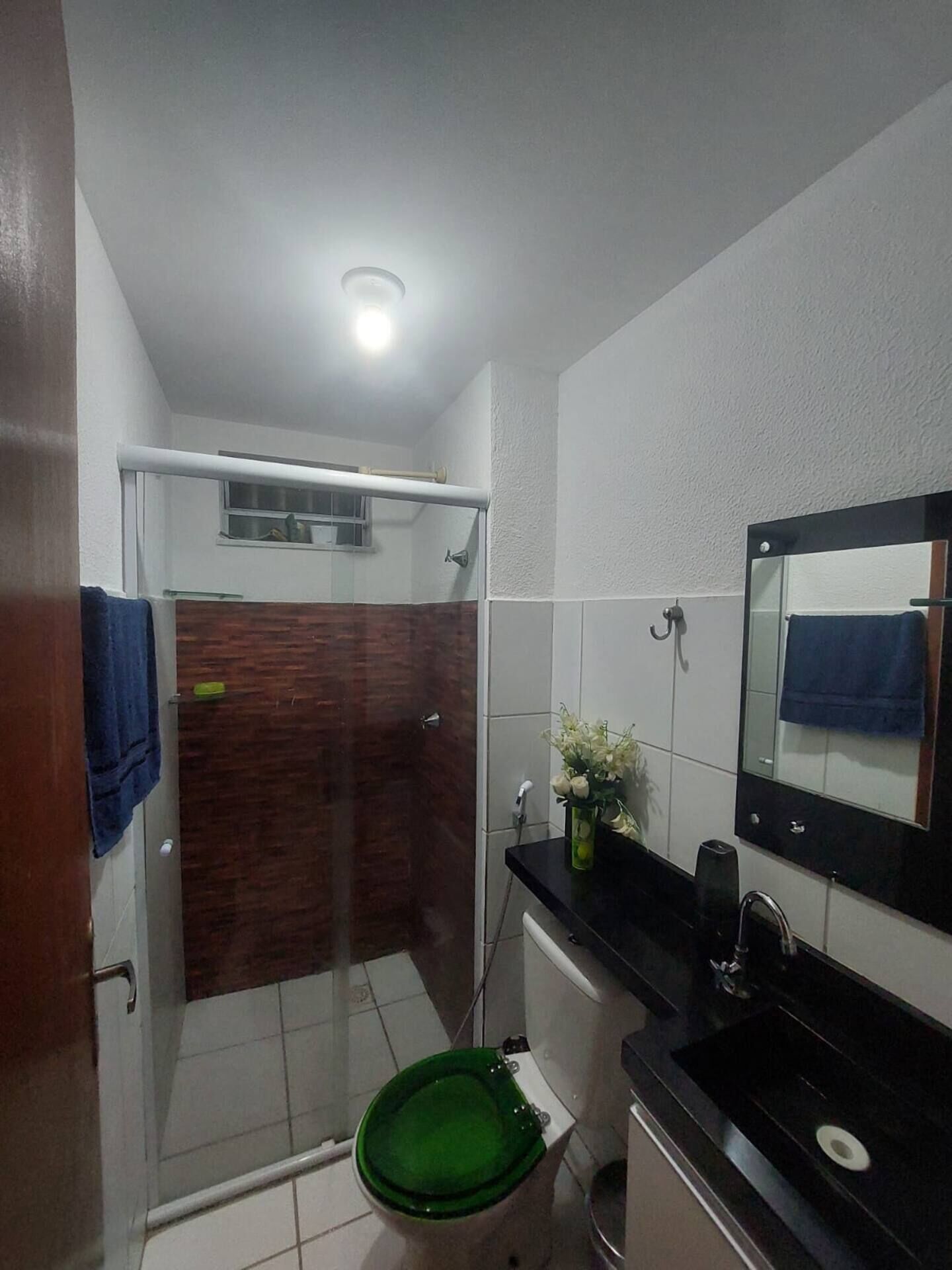 Een badkamer met douche, toilet, wastafel en een spiegel.