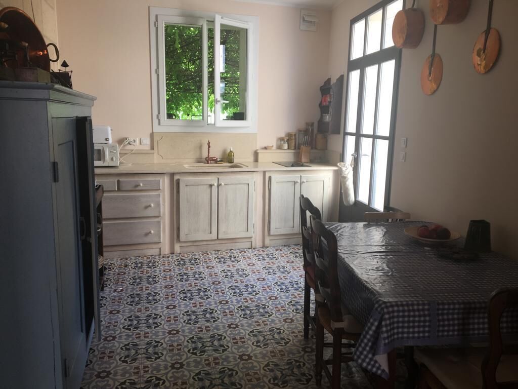 Une cuisine avec un carrelage décoratif, une table à manger avec des chaises et une fenêtre donnant sur un paysage verdoyant.