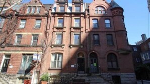 A red brick building with a central entrance, multiple windows, and a corner turret. - Rittenhouse Modern (Philadelphia)