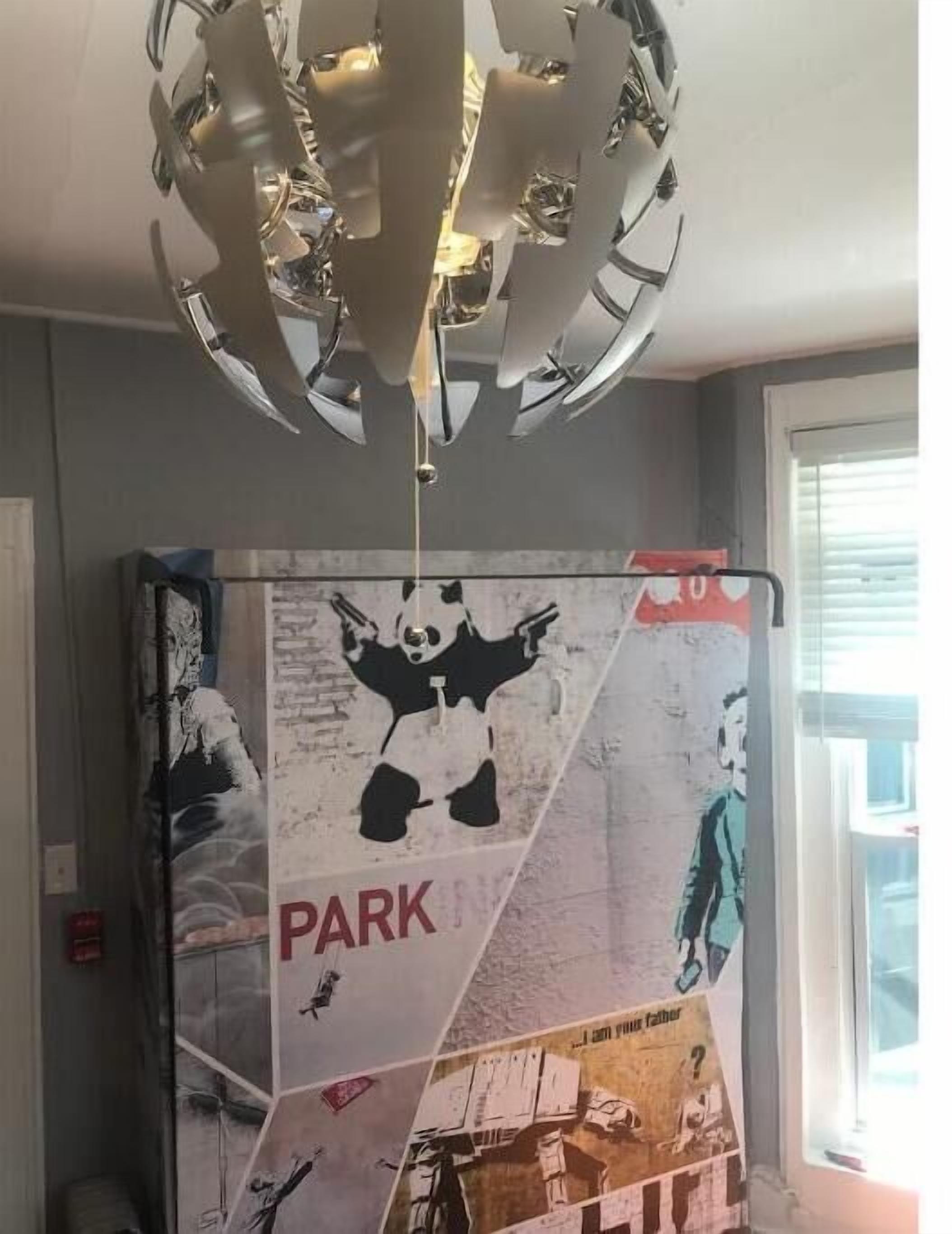 Une pièce avec un luminaire au plafond et une grande affiche accrochée au mur.