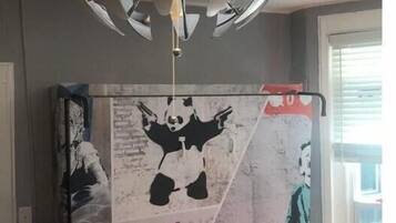Une pièce avec un luminaire au plafond et une grande affiche accrochée au mur.