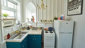 Une cuisine avec des armoires blanches, un plan de travail bleu, une cuisinière, un évier et un réfrigérateur.