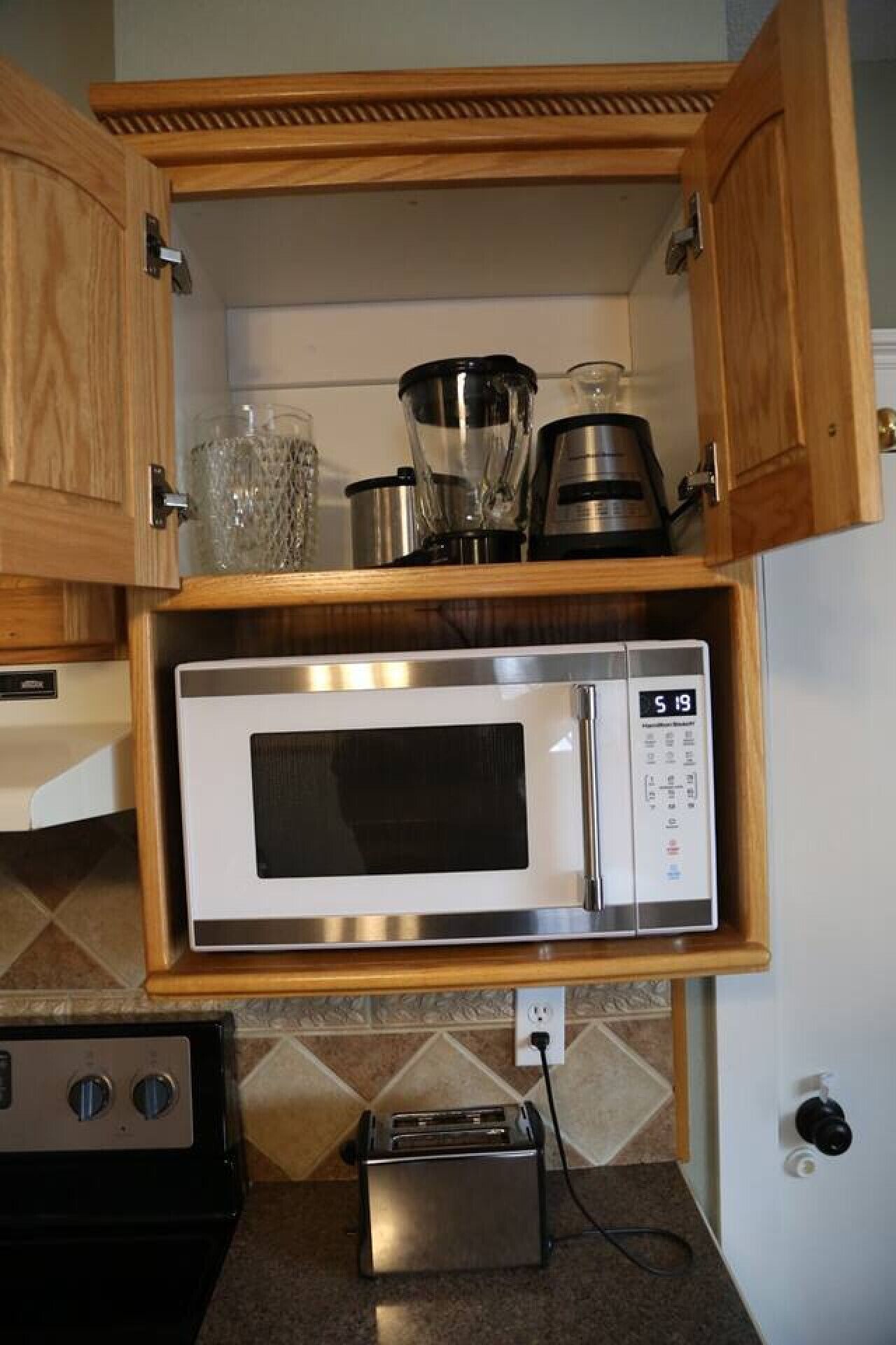 Eine Küche mit eingebauter Mikrowelle, einem Toaster und einem Mixer auf einem Regal.