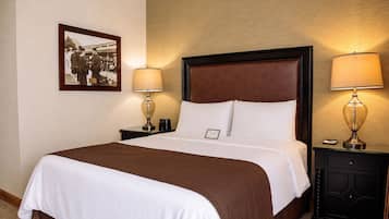 Habitación de hotel con una cama grande, dos mesitas de noche y dos lámparas. También se observa un cuadro en la pared.