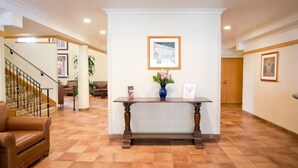 A reception area with a wooden reception desk, framed pictures on the walls, and a staircase in the background. - The Inn at UCLA (Los Angeles)