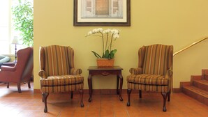 A room with two striped armchairs, a small table with a plant, and a framed picture on the wall. - The Inn at UCLA (Los Angeles)