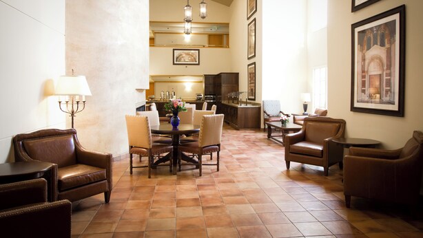 A spacious dining area with a high ceiling, a kitchen in the background, and a view of the cityscape through the windows. - The Inn at UCLA (Los Angeles)