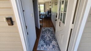 Un couloir avec une porte, un paillasson et un lit avec une couverture.