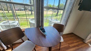 Un coin repas avec une table ronde, deux chaises et une fenêtre donnant sur une cour.