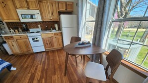 Une cuisine avec des meubles de rangement en bois, un four à micro-ondes, un réfrigérateur et une table à manger avec des chaises.