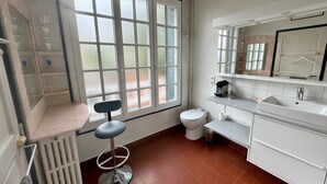 Ein Badezimmer mit Toilette, Waschbecken, Spiegel und einem Fenster mit Milchglas.