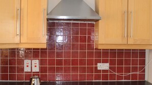 A kitchen with wooden cabinets, a black oven, and a red-tiled backsplash.