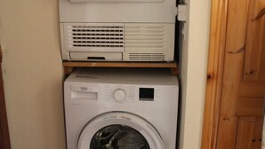 A compact laundry area with stacked appliances including a dryer and a washing machine.