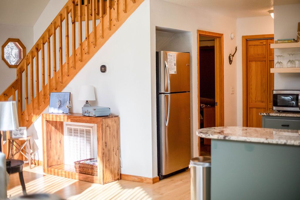 A kitchen with a wooden staircase, a stainless steel refrigerator, and a microwave.