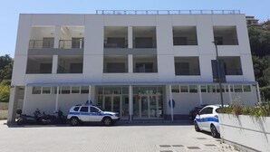 Il s’agit d’un bâtiment moderne doté d’un toit plat, de grandes fenêtres et d’une entrée en verre. Deux voitures de police sont garées devant.